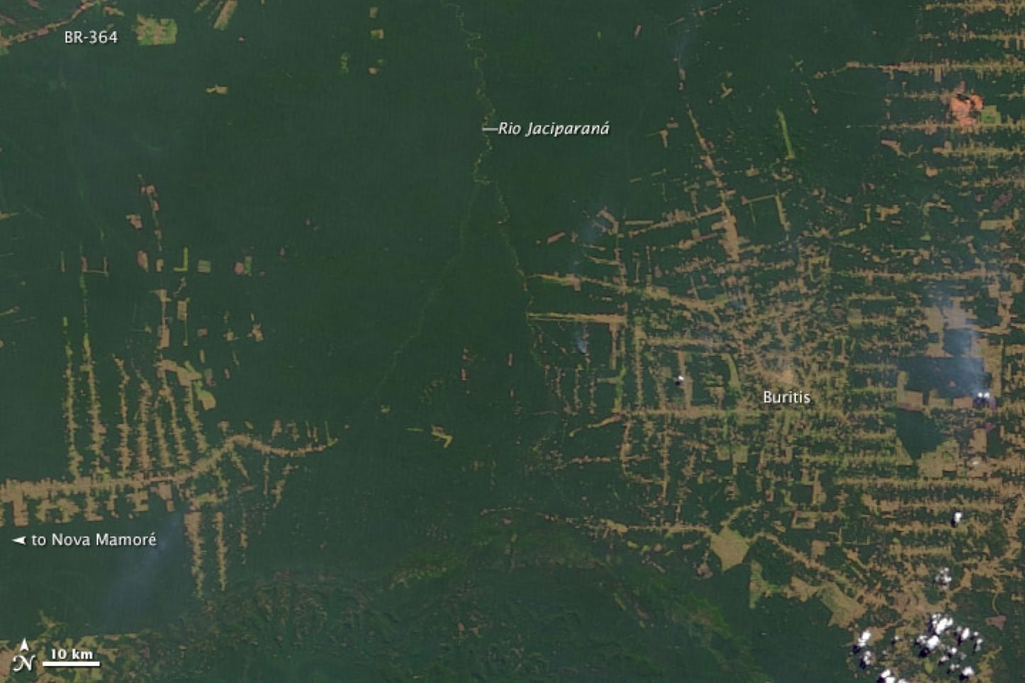 Satellite image showing deforestation patterns in a dense forest area, with visible cleared sections and remaining green forest.
