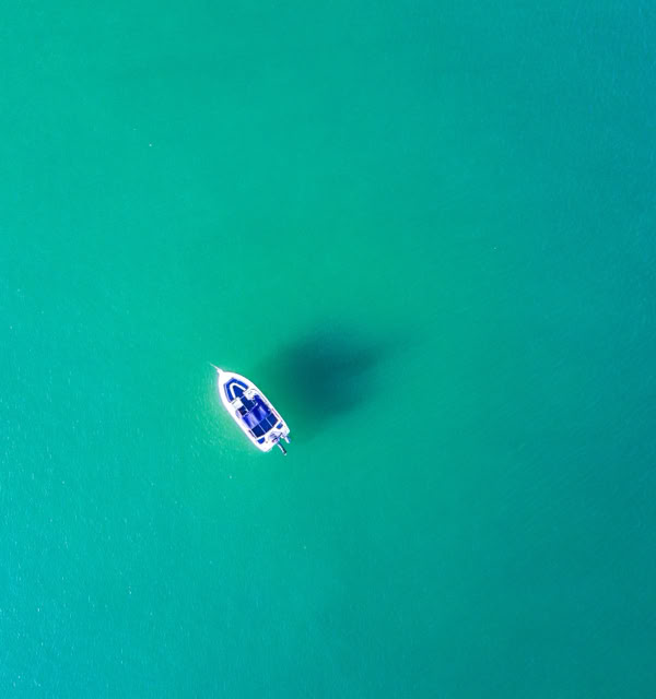 Aerial view of a small boat on clear turquoise water.